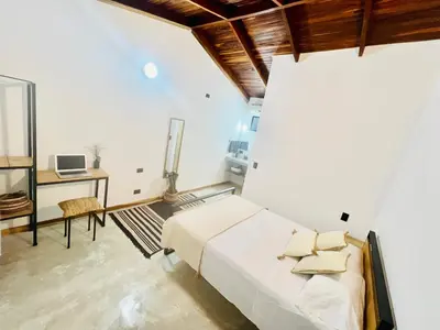 a white bedroom with a bed and a desk at Calipso Ocean Lodge- Avellana Beach Hotel in Playa Avellana