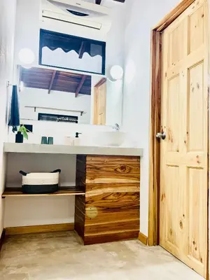 a bathroom with a sink and a wooden door at Calipso Ocean Lodge- Avellana Beach Hotel in Playa Avellana