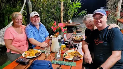 a group of people sitting at a table with food at Chalets Silencio del Bosque in Fortuna