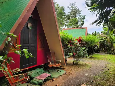 a red house with two chairs and a door at Chalets Silencio del Bosque in Fortuna