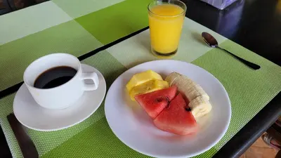 a plate of fruit and a cup of coffee on a table at Chalets Silencio del Bosque in Fortuna