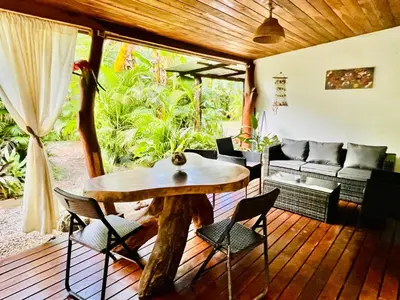 a wooden porch with a wooden table and chairs at Lovely rental unit in Nosara- steps from the beach in Nosara