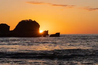 a sunset over the ocean with a rock in the water at Lovely rental unit in Nosara- steps from the beach in Nosara
