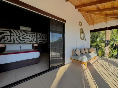 a bedroom with a bed and a chair on a balcony at Oxygen Jungle Villas & Spa in Uvita