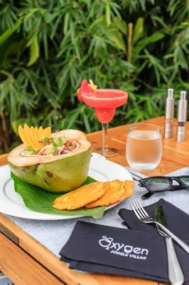 a wooden table with a plate of food and a drink at Oxygen Jungle Villas & Spa in Uvita