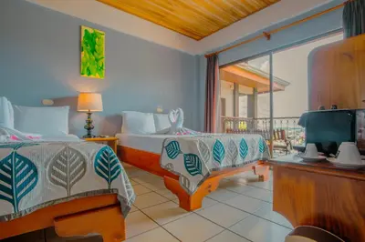 a bedroom with two beds and a tv and a balcony at La Fortuna Downtown Boutique Hotel in Fortuna