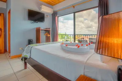 a bedroom with a large bed with a large window at La Fortuna Downtown Boutique Hotel in Fortuna