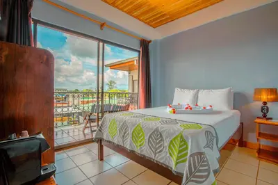 a bedroom with a bed and a large window at La Fortuna Downtown Boutique Hotel in Fortuna