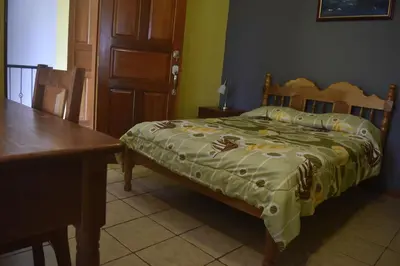 a bedroom with a bed and a table and a door at Hotel Santa Ana Liberia Airport in Liberia