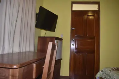 a room with a table and a television and a door at Hotel Santa Ana Liberia Airport in Liberia