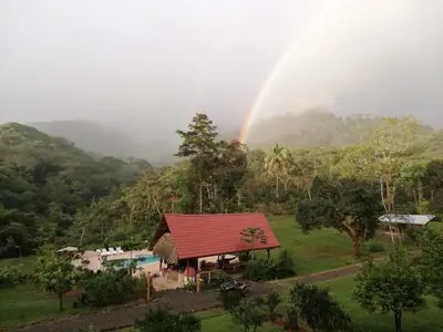 a rainbow over a small house with a pool at Hacienda Mil Bellezas - Private 40ha Jungle Reserve in Quepos