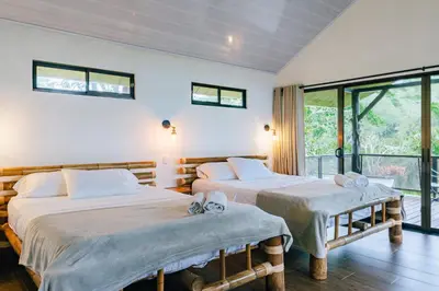 two beds in a room with a window at Hacienda Mil Bellezas - Private 40ha Jungle Reserve in Quepos