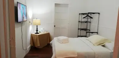 a bedroom with a white bed and a table with a lamp at Casa Mayela Guest House in San José