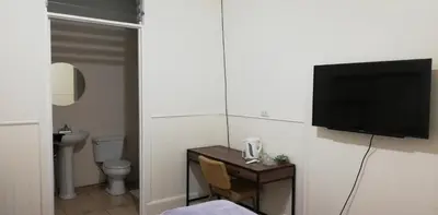 a bathroom with a toilet and a television on a wall at Casa Mayela Guest House in San José