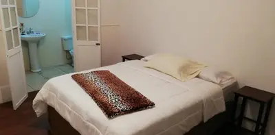 a bedroom with a bed with a brown scarf on it at Casa Mayela Guest House in San José