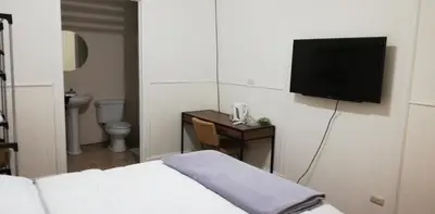 a hotel room with a bed and a tv on a wall at Casa Mayela Guest House in San José
