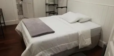 a white bed with a blanket and pillows on it at Casa Mayela Guest House in San José