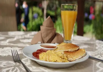 a plate of breakfast food and a glass of orange juice at Hotel de Montaña Suria in San Gerardo de Dota