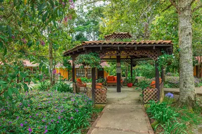 a wooden gazebo in a garden with flowers at Hotel de Montaña Suria in San Gerardo de Dota