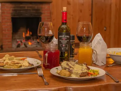 a table with two plates of food and two glasses of wine at Hotel de Montaña Suria in San Gerardo de Dota