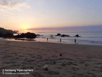 a group of people playing on the beach at sunset at Garden of Heliconias Lodge in Drake