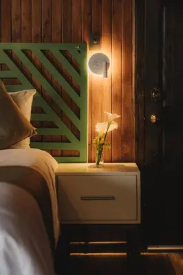 a bed with a night stand with a vase of flowers on it at Lauraceas Lodge in San Gerardo de Dota