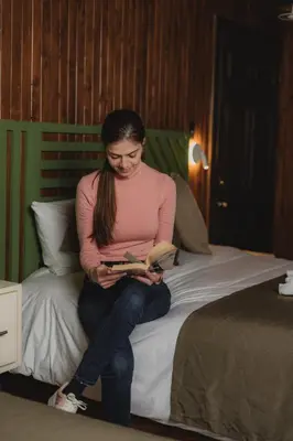 a woman sitting on a bed reading a book at Lauraceas Lodge in San Gerardo de Dota