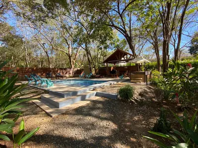 a swimming pool in a yard with chairs and trees at CASA NATURaL in Brasilito