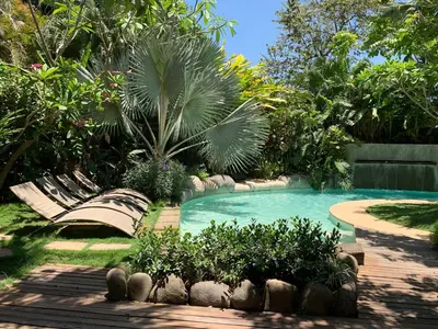 a swimming pool with benches in a garden at Villa Don Vito in Tamarindo