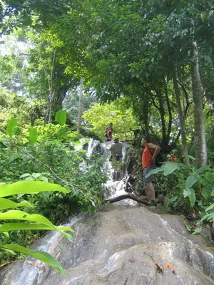 a man standing on a rock next to a waterfall at Fidelito Ranch & Lodge in Tambor
