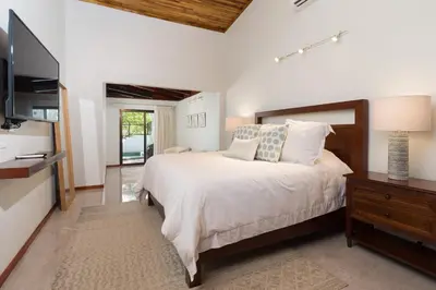 a bedroom with a large bed and a television at Casa Woodbine Private House on Tamarindo Beach in Tamarindo