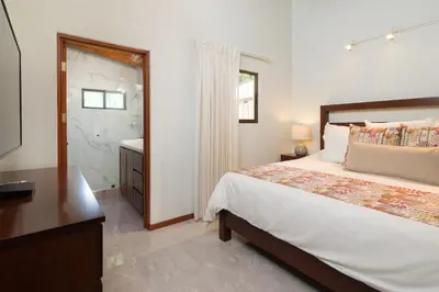 a bedroom with a bed and a bathroom with a sink at Casa Woodbine Private House on Tamarindo Beach in Tamarindo