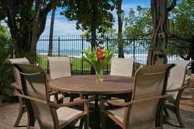 a wooden table with chairs and a vase of flowers at Casa Woodbine Private House on Tamarindo Beach in Tamarindo