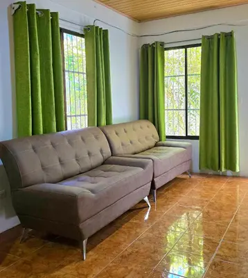 a living room with a couch and green curtains at HOUSE CATTLEYA monteverde in Monteverde Costa Rica