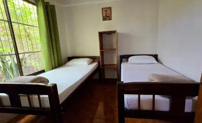two twin beds in a room with a window at HOUSE CATTLEYA monteverde in Monteverde Costa Rica