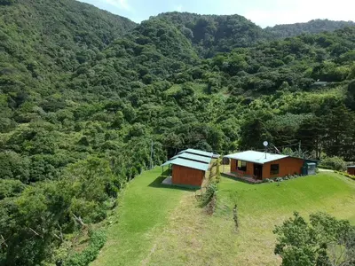 a small house on a grassy hill in front of a mountain at Casitas de Montaña Cabuya in Monteverde Costa Rica