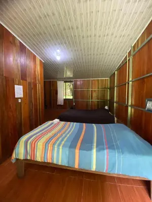 a bed in a small room with wood paneling at Casitas de Montaña Cabuya in Monteverde Costa Rica