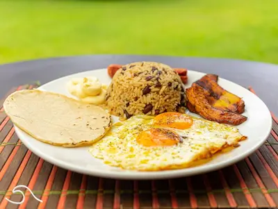 a plate of breakfast food with eggs bacon and toast at Tranquilidad Resort in Parrita