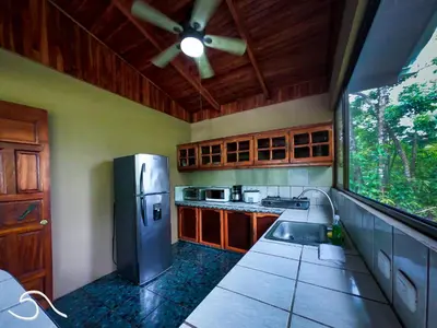 a kitchen with a stainless steel refrigerator and a window at Tranquilidad Resort in Parrita