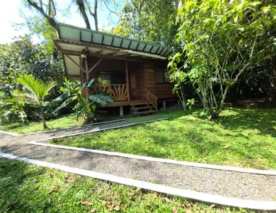 a small cabin with a bench in the grass at Centro Ananda, Cabina, Bambuszelt in Guápiles