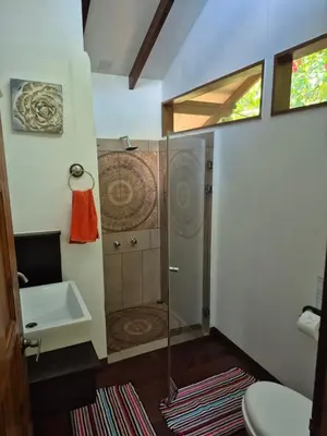 a bathroom with a shower with a toilet and a sink at Centro Ananda, Cabina, Bambuszelt in Guápiles