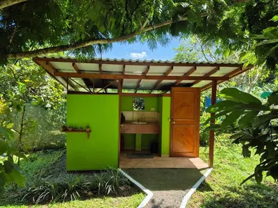 a green house with a wooden roof in a garden at Centro Ananda, Cabina, Bambuszelt in Guápiles