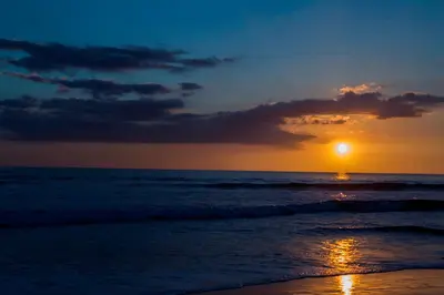 a sunset on a beach with the ocean at Hotel Los Ranchos in Jacó