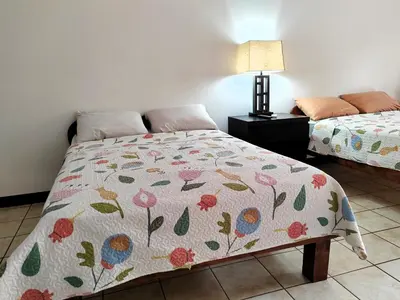 a bedroom with a bed with a floral comforter at Hotel Los Ranchos in Jacó