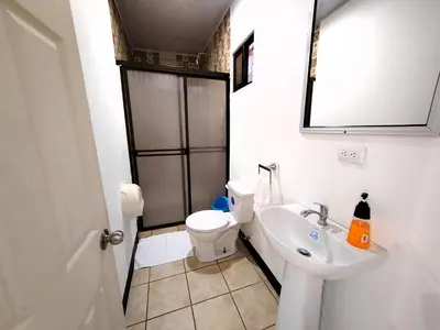 a bathroom with a sink and a toilet and a mirror at Hotel Los Ranchos in Jacó