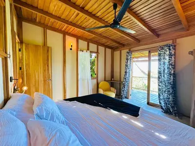 a bedroom with a large bed with a ceiling fan at Calamocha Lodge in Santa Teresa Beach