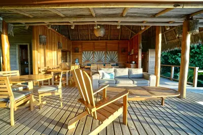 a porch with a couch and a table and chairs at Calamocha Lodge in Santa Teresa Beach