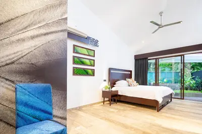 a bedroom with a bed and a blue chair at Pumilio Mountain & Ocean Hotel in Jacó