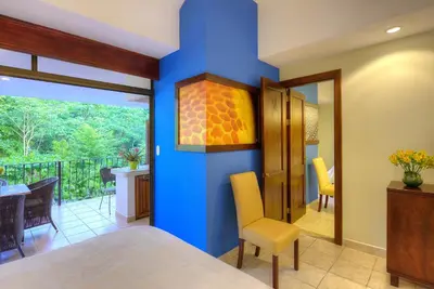 a room with a blue wall and a dining room at Pumilio Mountain & Ocean Hotel in Jacó