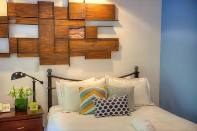 a bedroom with a bed with a wooden wall at Pumilio Mountain & Ocean Hotel in Jacó